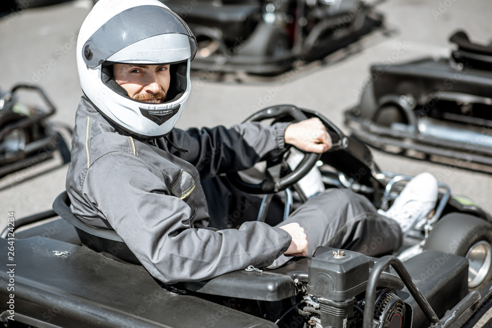 一名身穿运动服、戴着防护头盔的男性赛车手坐在赛道外的卡丁车上的肖像