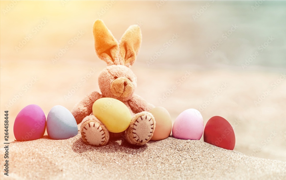 Easter bunny and color eggs on beach sand
