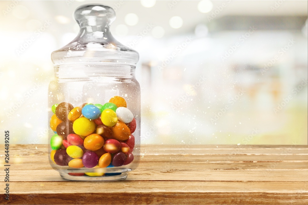 Transparent glass jar with colorful chocolate candies
