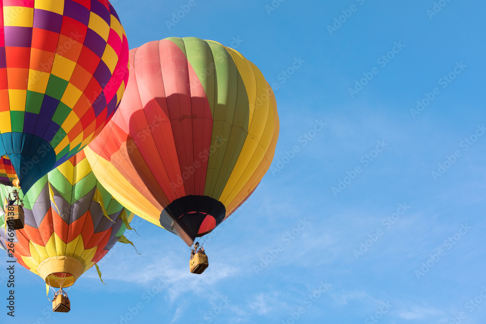 三个五颜六色的热气球在蓝天上相互靠近飞行