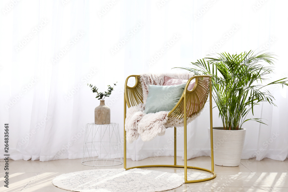 Stylish armchair near light curtains in room