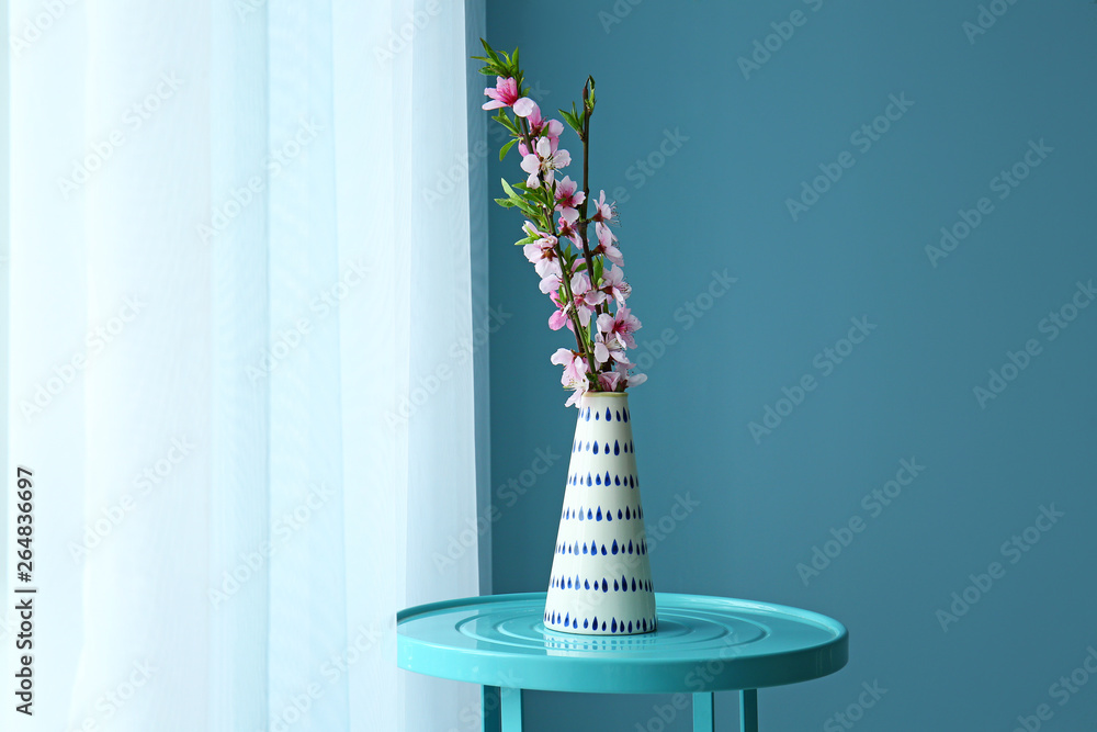 房间窗户附近的桌子上放着一个花瓶，花瓶上有美丽的开花的树枝