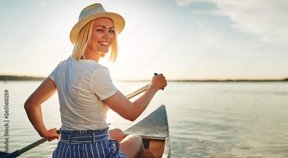 微笑的年轻女子夏天在湖面上划独木舟
