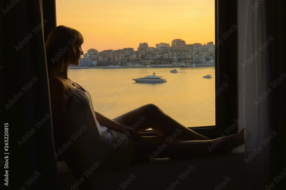 CLOSE UP: Woman sitting on a ledge, watching as the sun rises in Saranade.