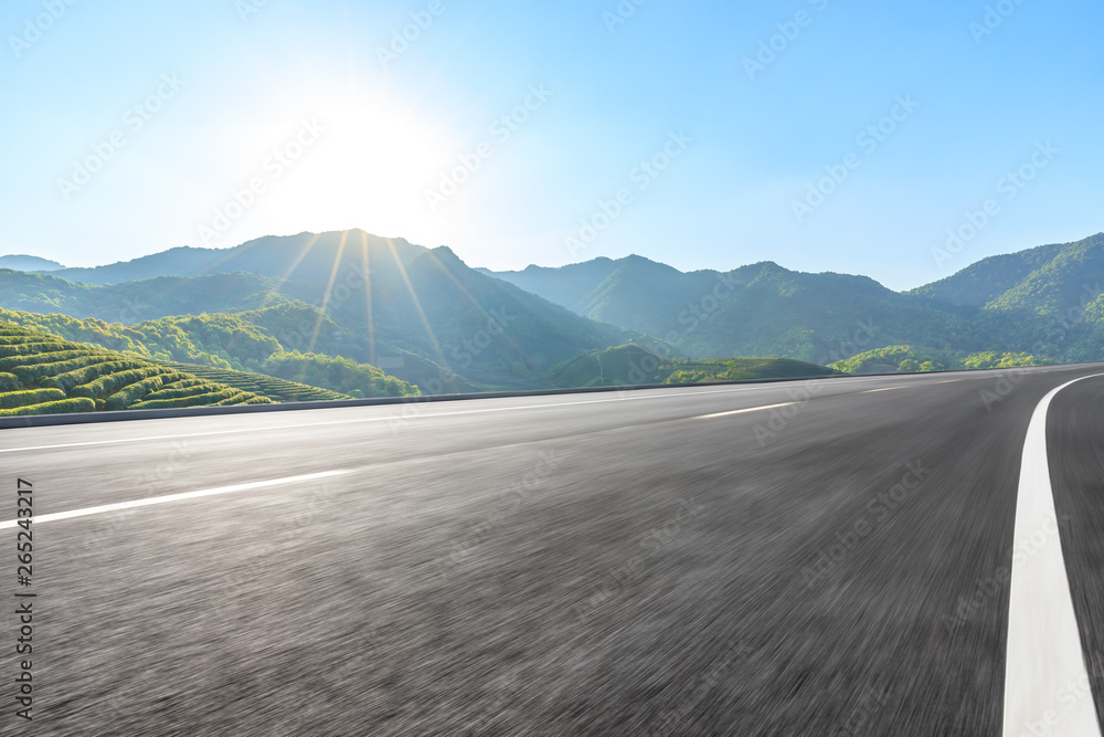 Motion blurred country road and green mountains natural landscape under the blue sky