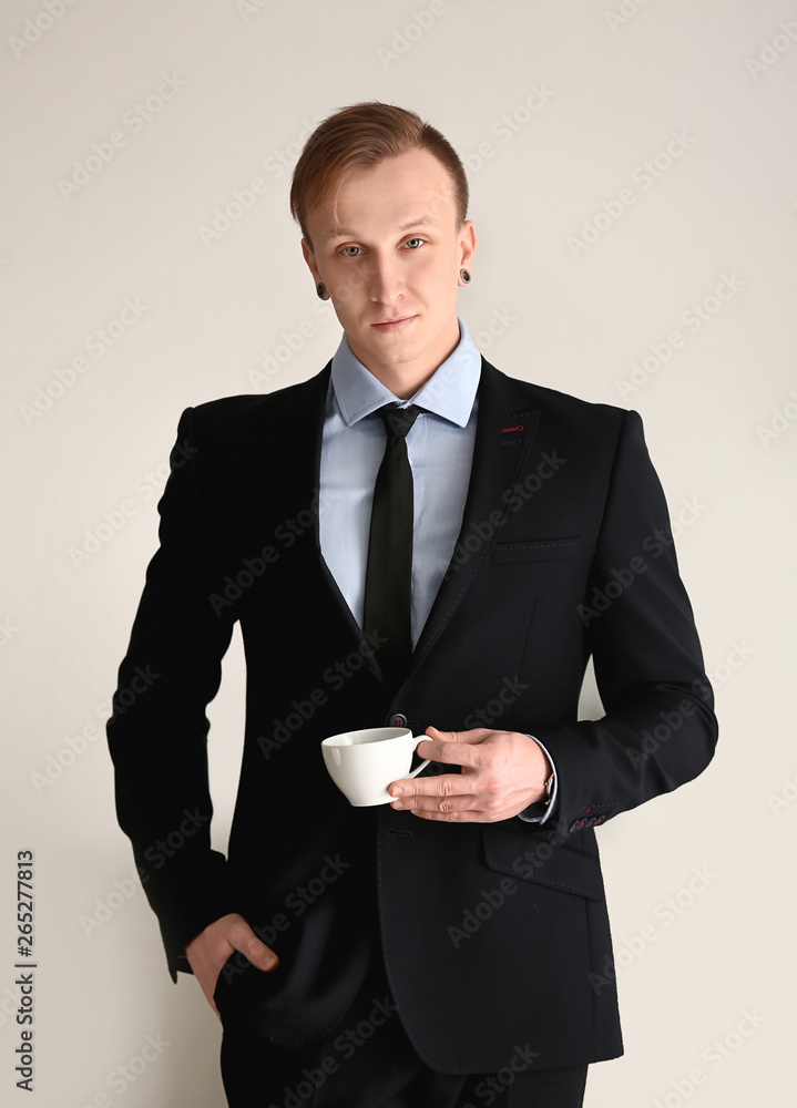 Handsome stylish businessman with cup of coffee in office