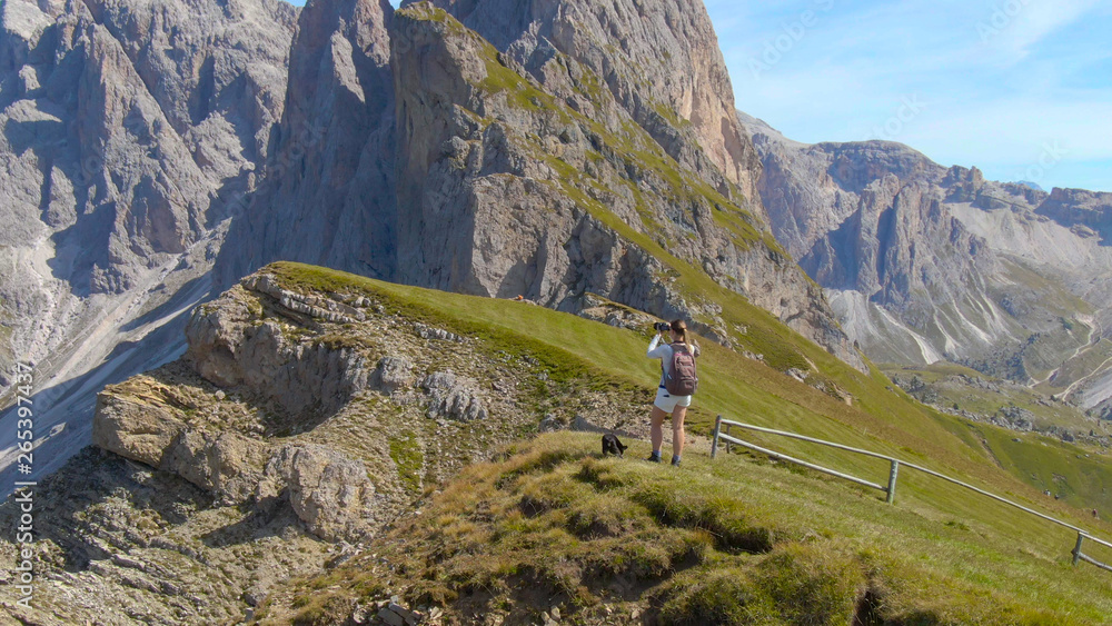 无人机：飞向在山上拍照的快乐的女徒步旅行者。