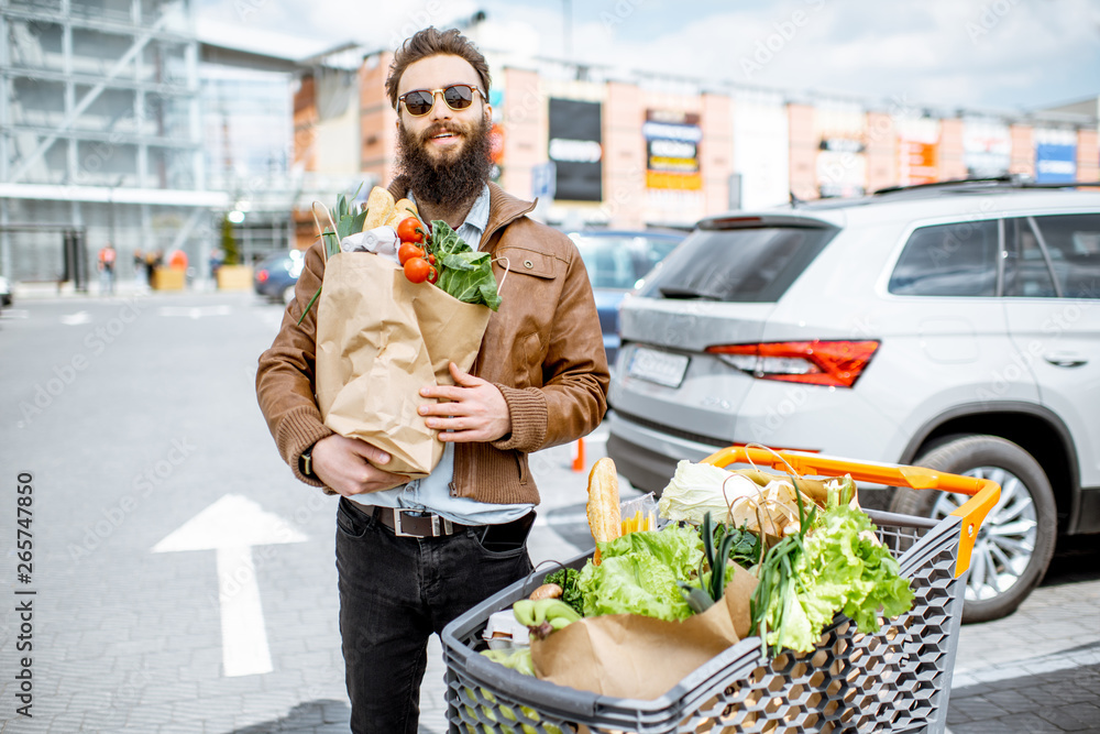 快乐时尚的男人，在超市附近的户外购物袋里装满了新鲜健康的食物