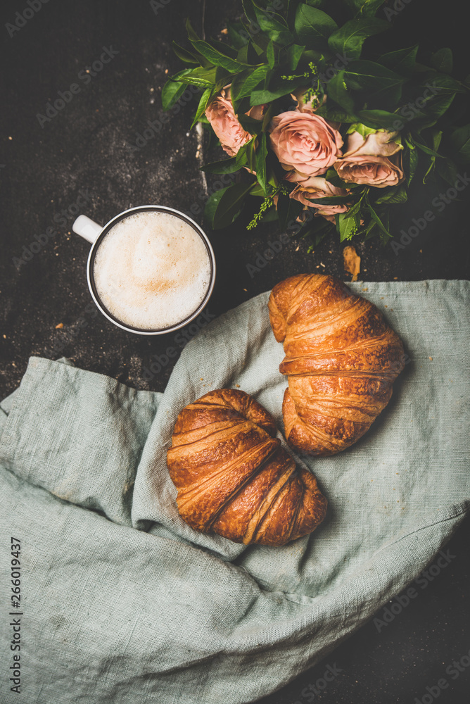Coffee break. Flat-lay of cup of hot cappuccino with fresh croissants on grey linen towel and bouque