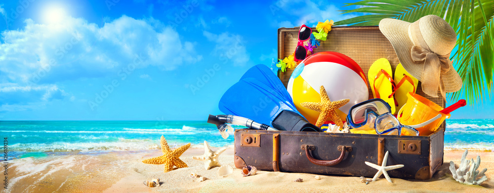 沙滩上手提箱里的海滩配件。家庭度假概念