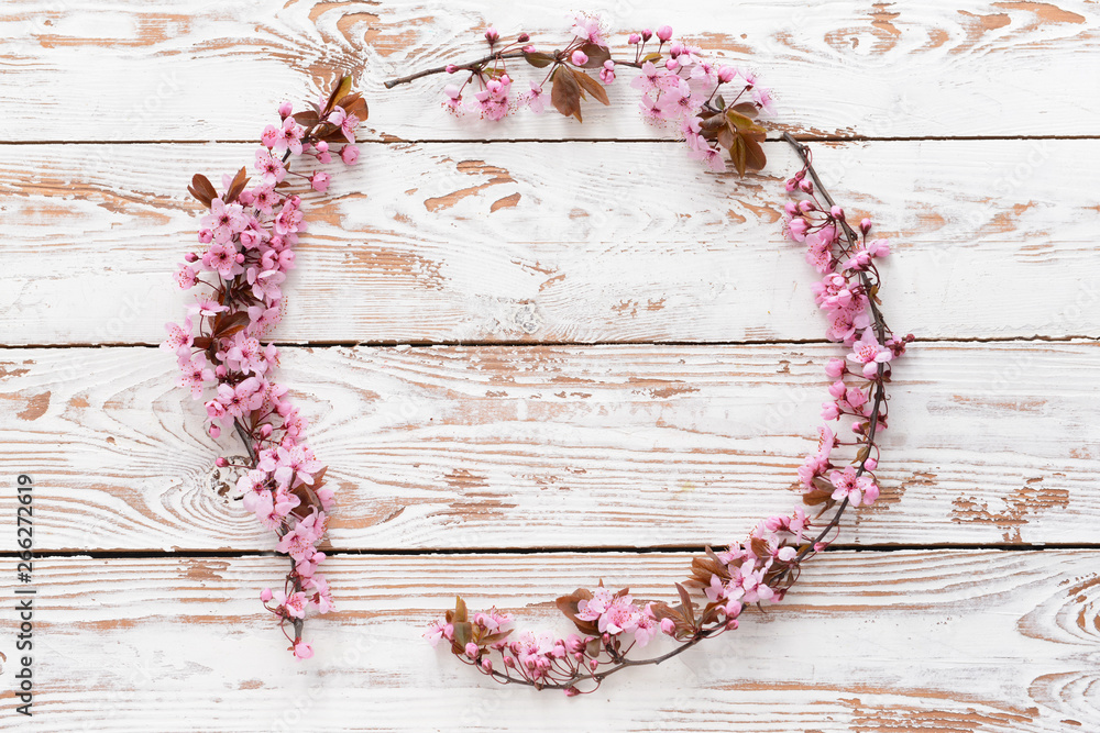 Circle made of beautiful blossoming branches on wooden background