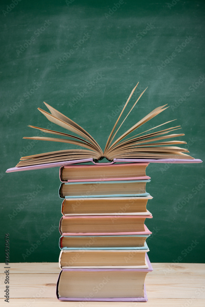教育与阅读理念——教室木桌上的一组五颜六色的书，黑板