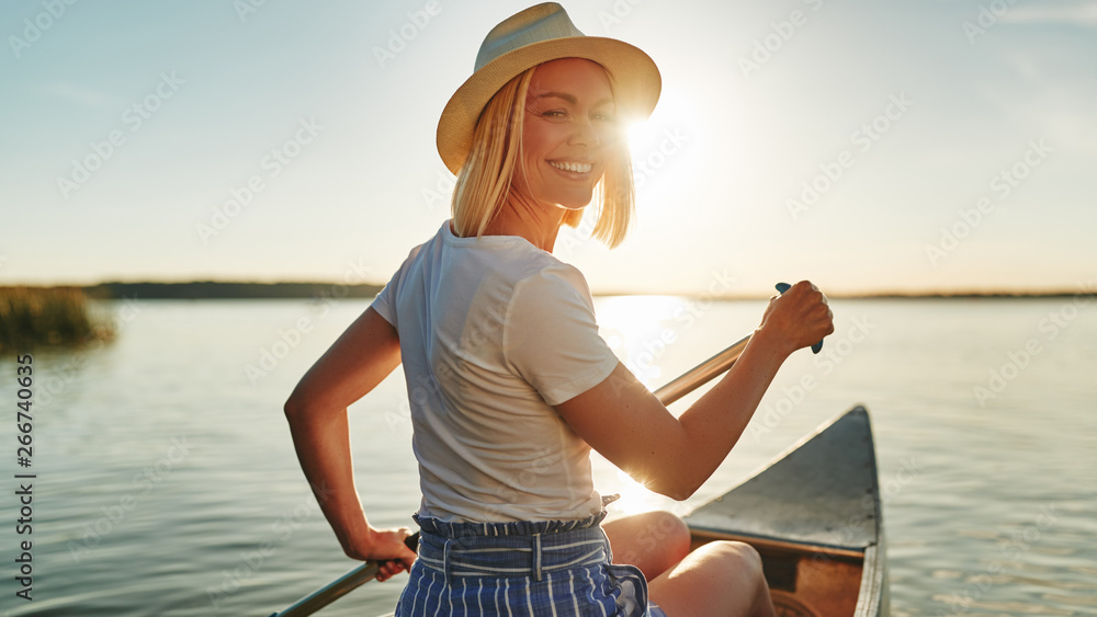 微笑的女人在夏天的湖面上划独木舟