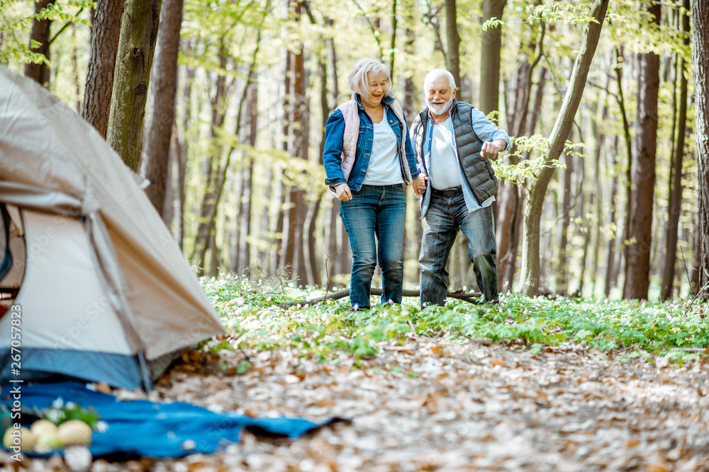 一对老年夫妇在森林中的露营地附近散步。退休后积极生活的概念