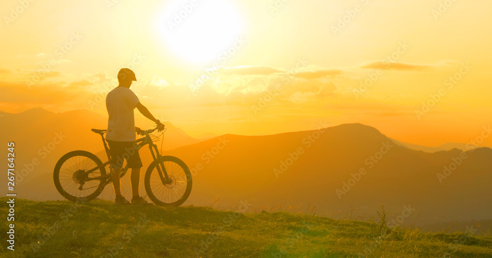 镜头闪光：一名男子在自行车旅行后休息，观察傍晚的风景。