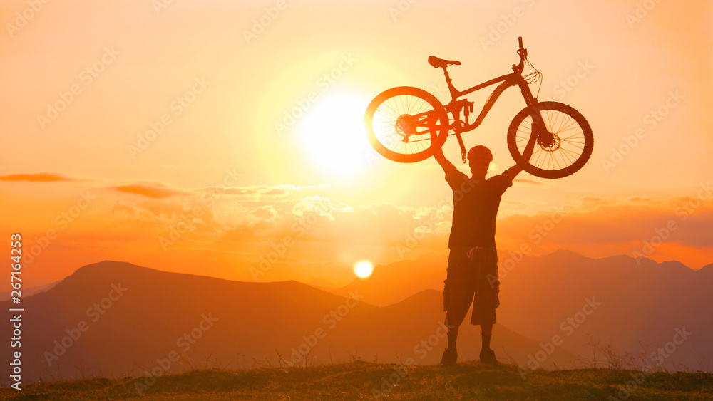 复制空间：一名兴奋的男子在一次成功的旅程后将自行车举过头顶。