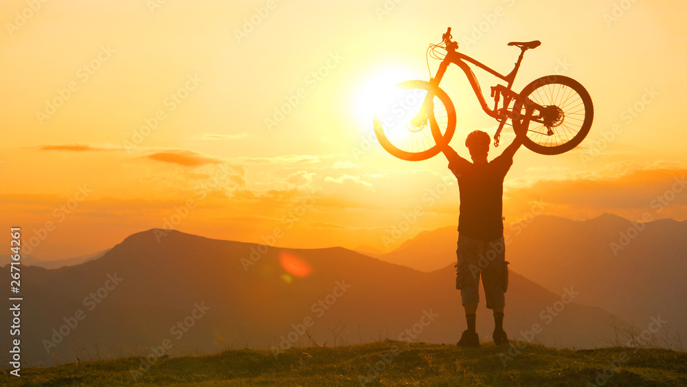 沉默：日出时，一名男性游客骑自行车上山后，将自行车举过头顶