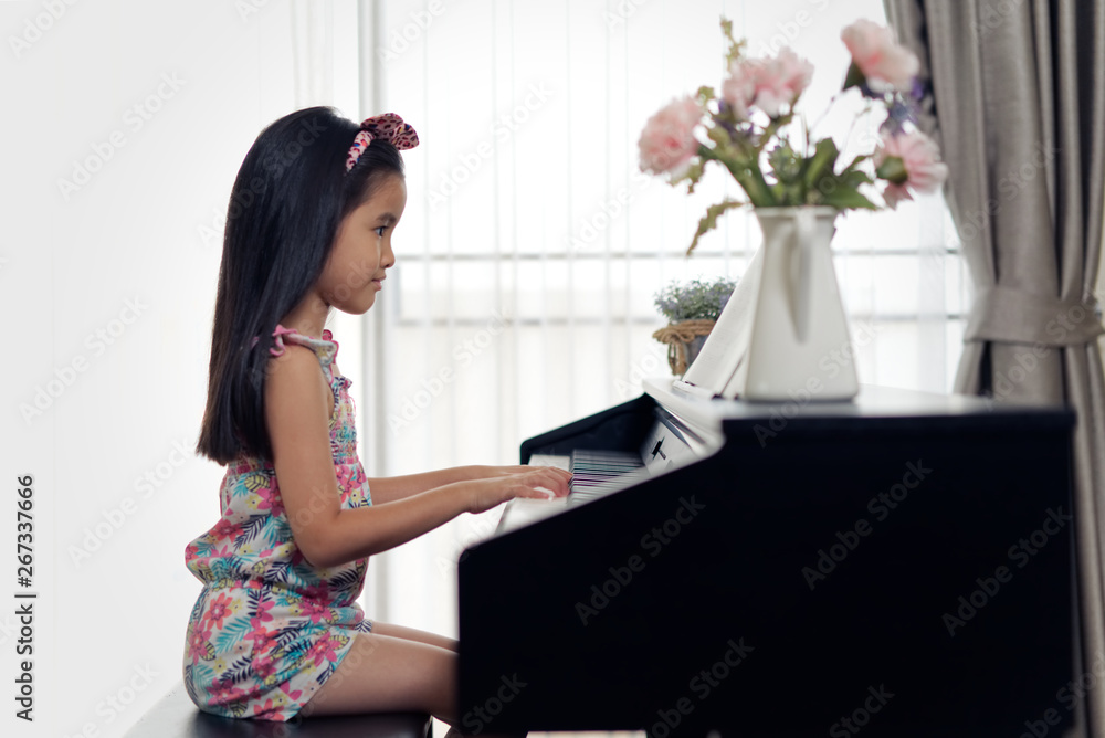 年轻的亚洲小可爱女孩在家弹电子钢琴的侧视图。从侧面看whil
