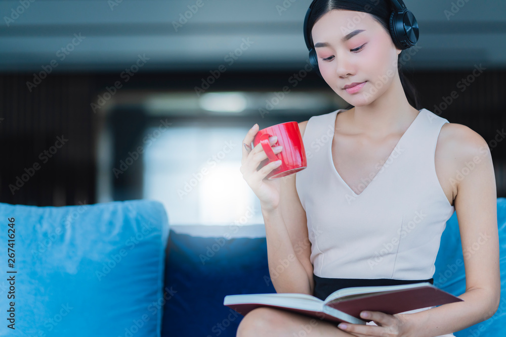穿着休闲工作服的亚洲女人在客厅沙发上喝咖啡和看杂志休息，伙计