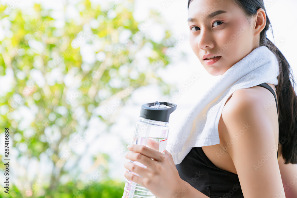 美丽的运动亚洲女性手持瑜伽垫和水瓶，进行健康健身瑜伽锻炼