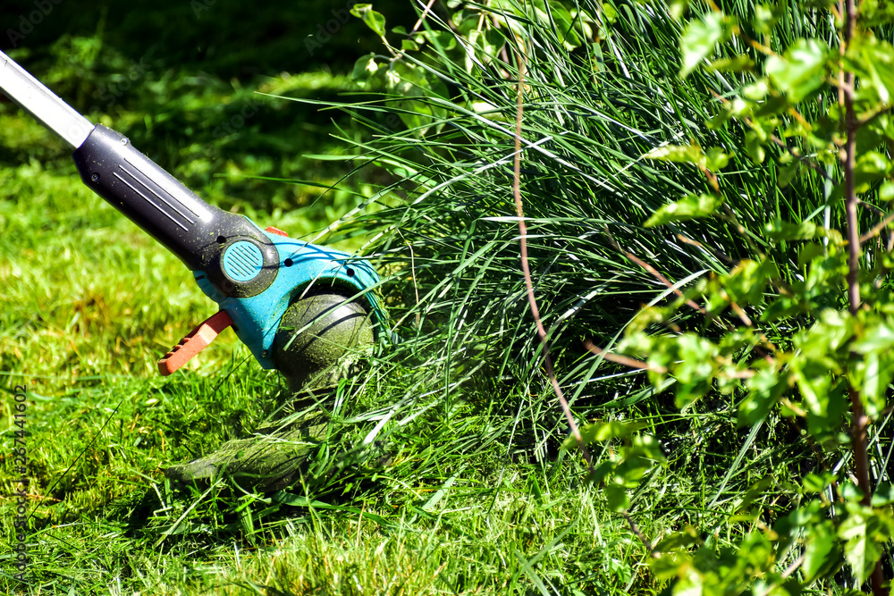 简单的生活方式，花园里的普通工作——男人用重型修剪草坪