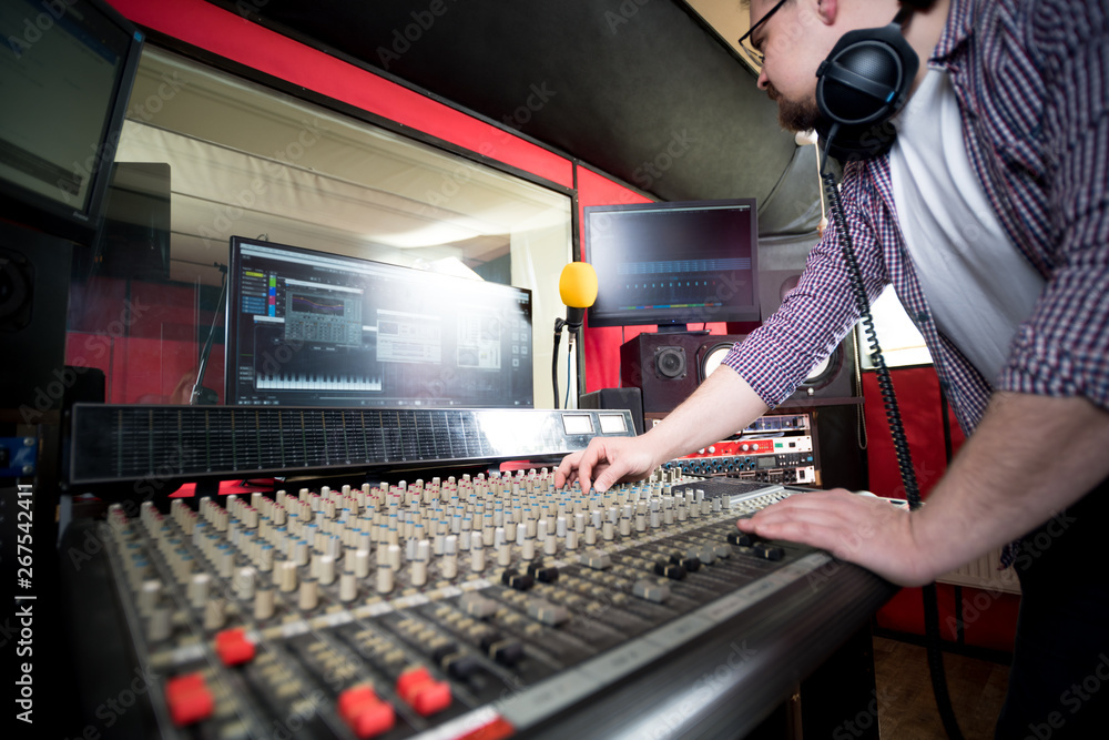 在录音室工作的声音制作人使用音板和监视器