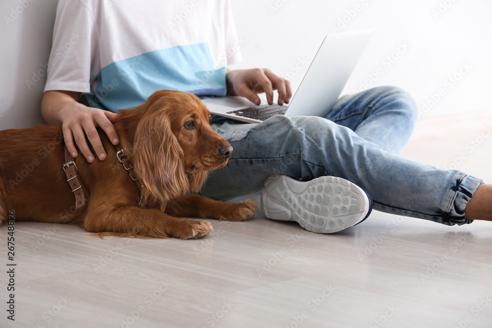 十几岁的男孩带着可爱的狗和笔记本电脑坐在光墙附近