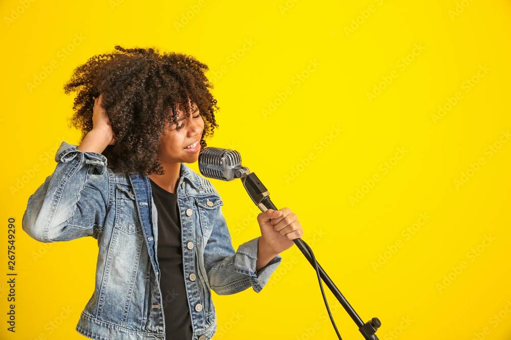 非洲裔美国女孩拿着麦克风在彩色背景下唱歌