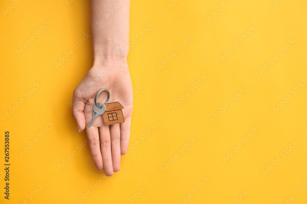 Female hand with key from house on color background