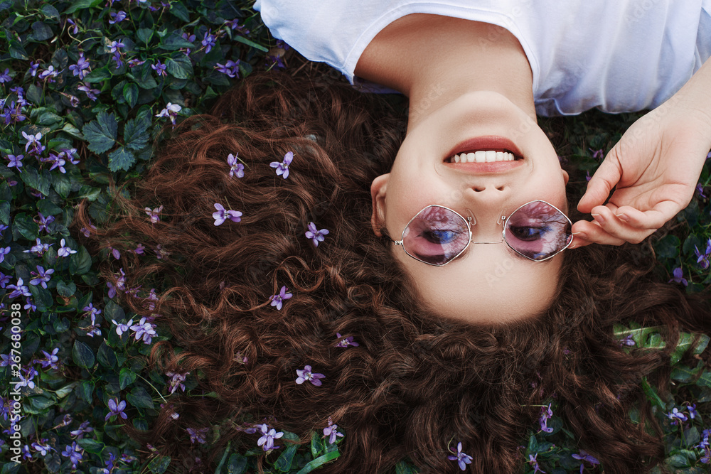 Outdoor flat lay, top view close up portrait of young beautiful happy smiling girl with long curly h