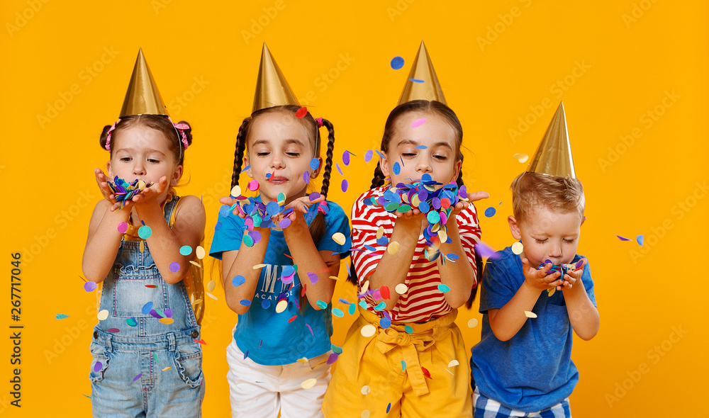 节日快乐的孩子们在黄色五彩纸屑中跳跃