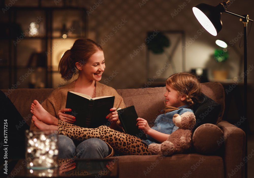 家人睡前，母亲晚上在灯旁给孩子女儿读书。