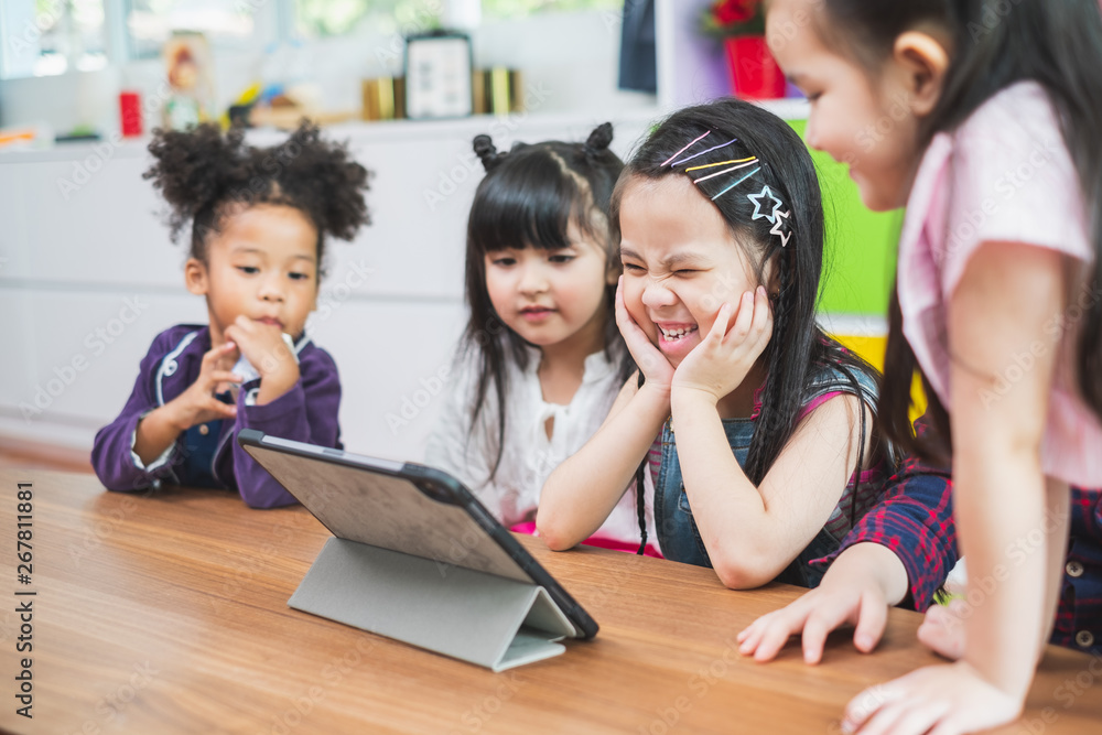 Group of diversity cute kids watching on tablet for lesson in classroom, education concept