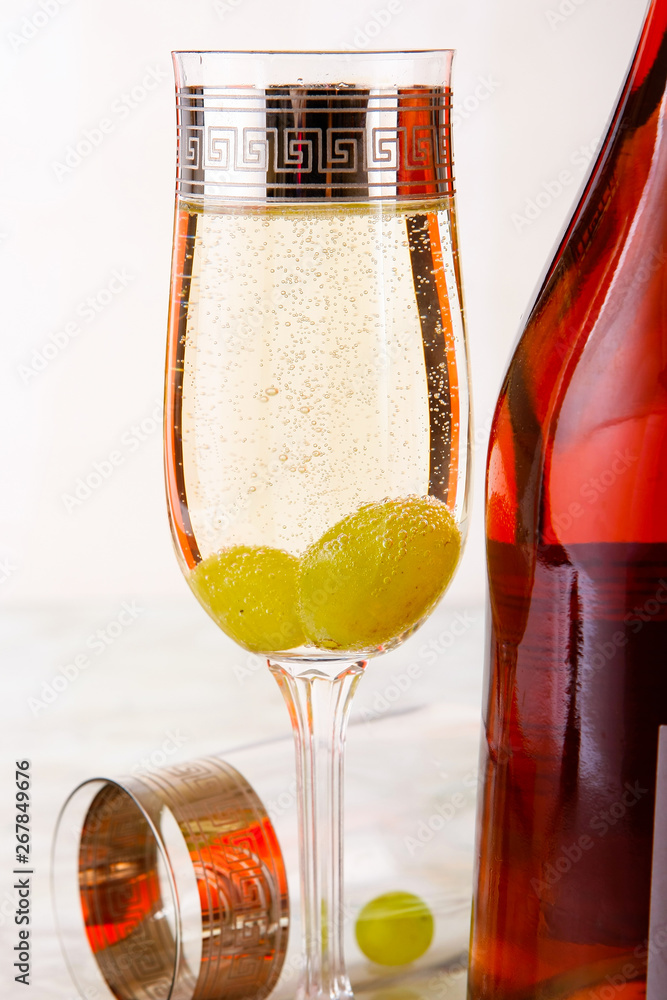 一杯白葡萄酒和一块冰，白桌子上放着葡萄。