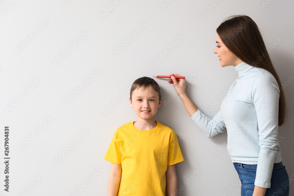 母亲在墙附近测量儿子的身高