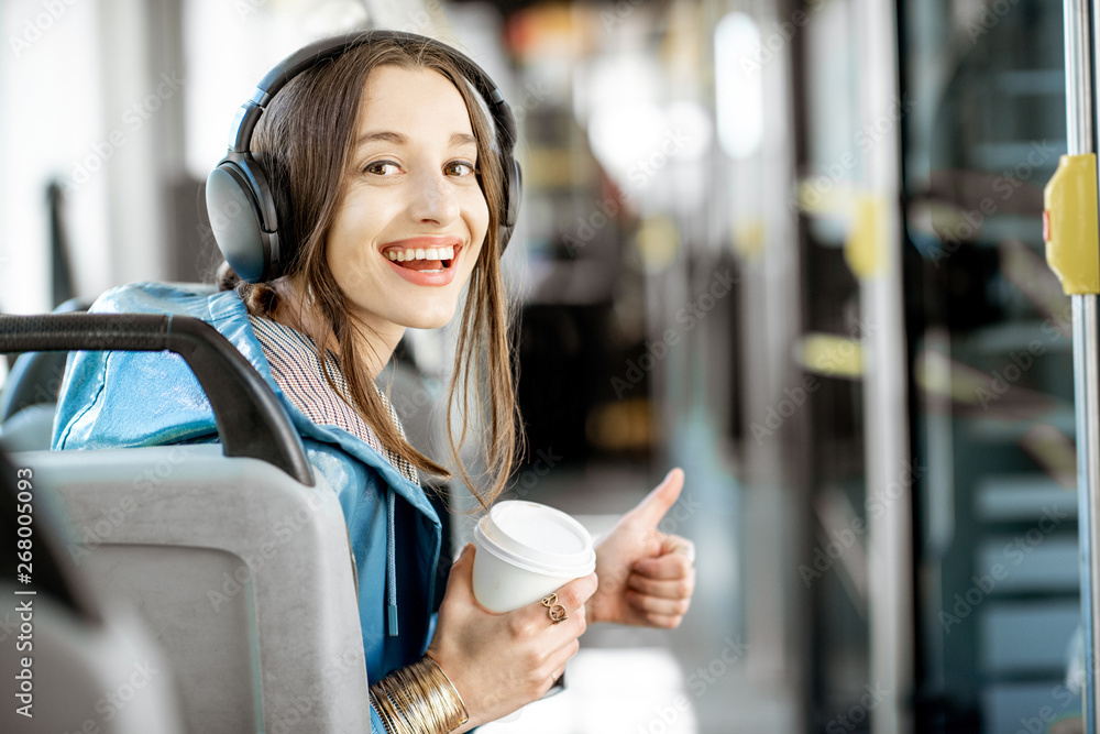 一位年轻女性乘客戴着耳机坐在公共交通工具上享受旅行的肖像i