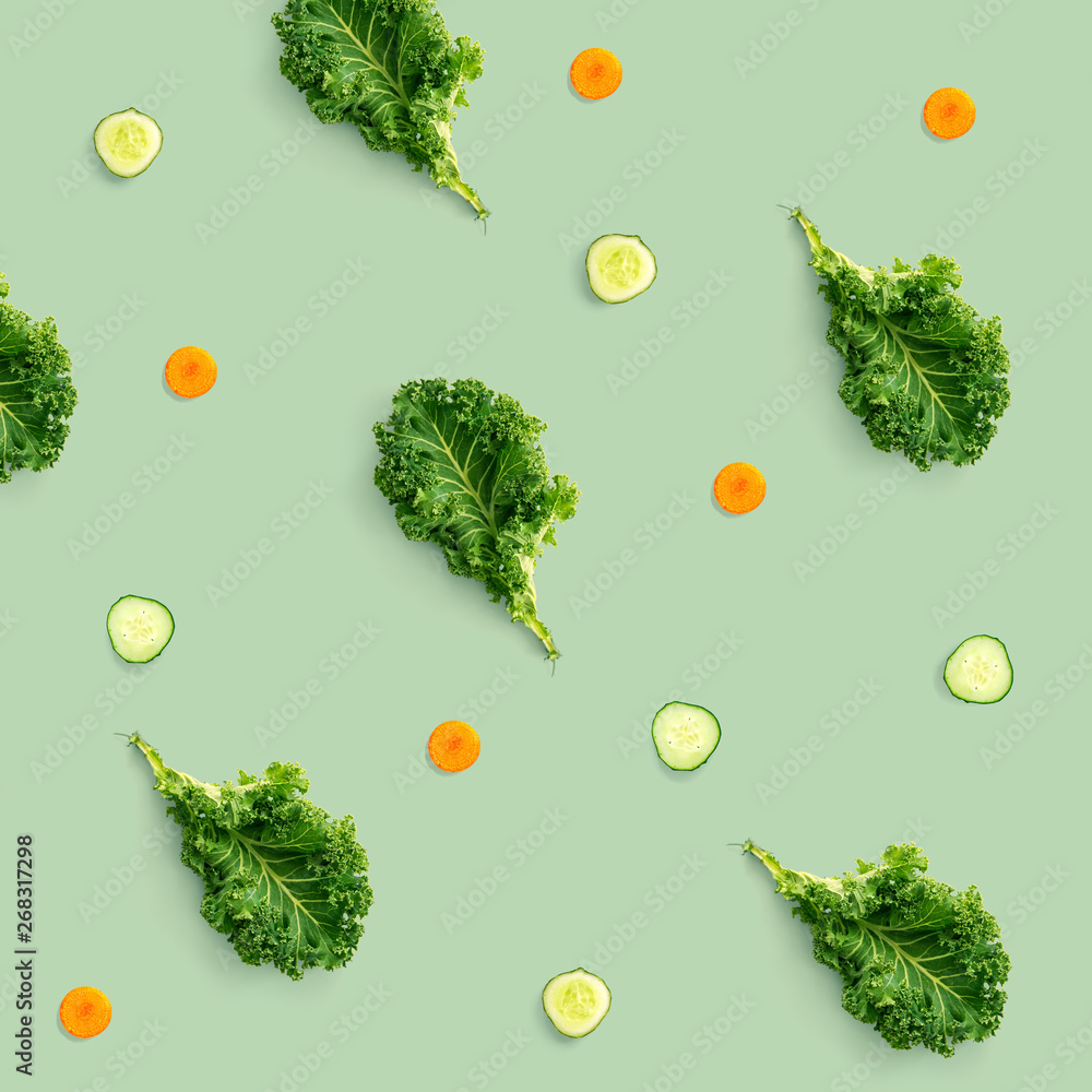 Creative pattern made of kale, cucumber and carrot on green background. Flat lay. Food concept.