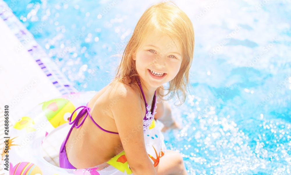 美丽的小女孩在泳池边晒太阳