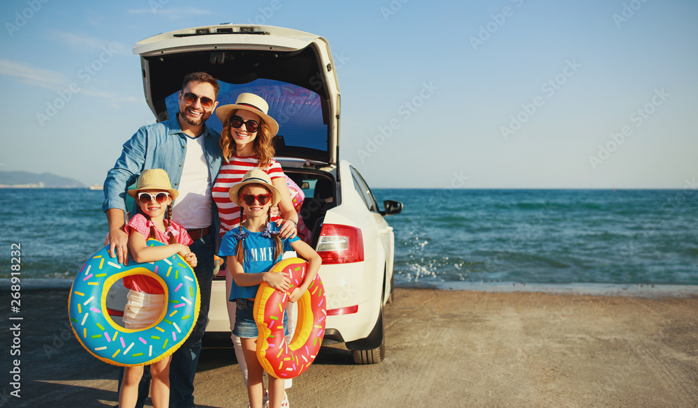 快乐的一家人在夏天的汽车之旅中在海滩上开车旅行。