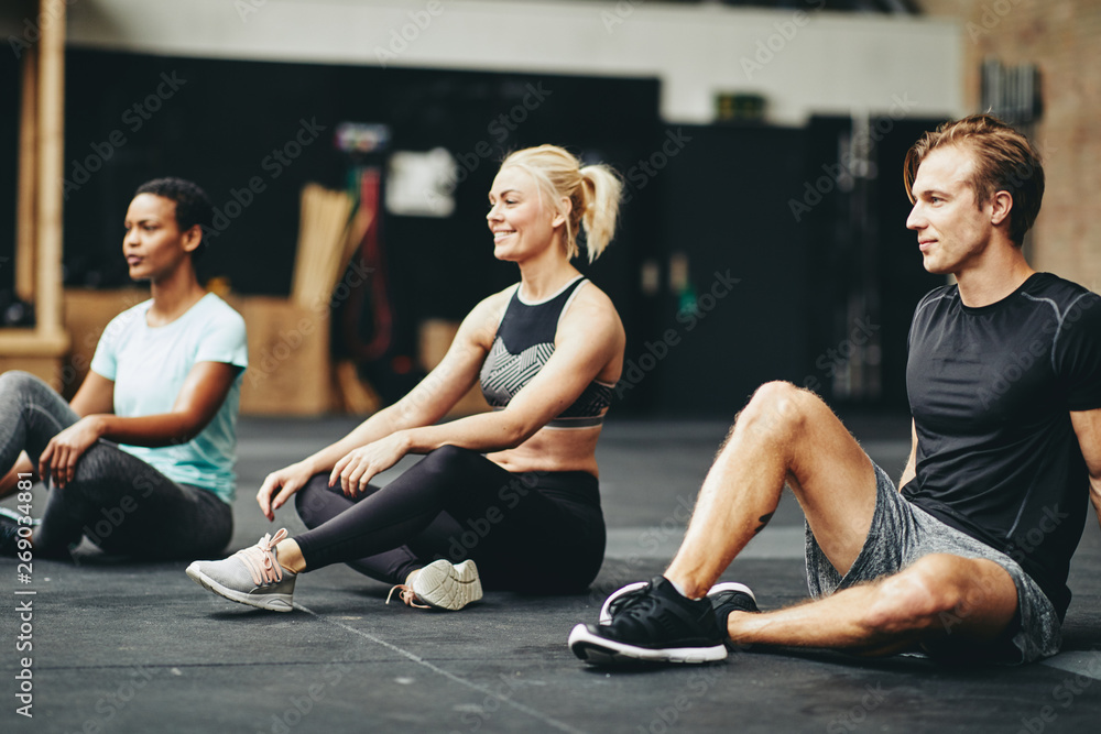 Smiling people relaxing on a gym floor after working out