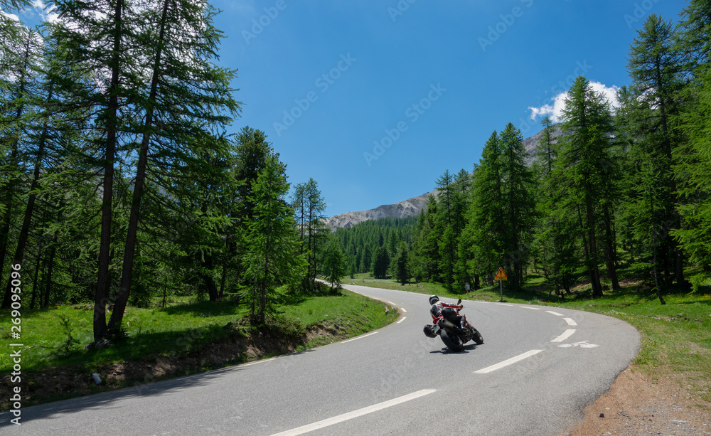 无法辨认的游客骑着摩托车进入森林的一个空转弯处