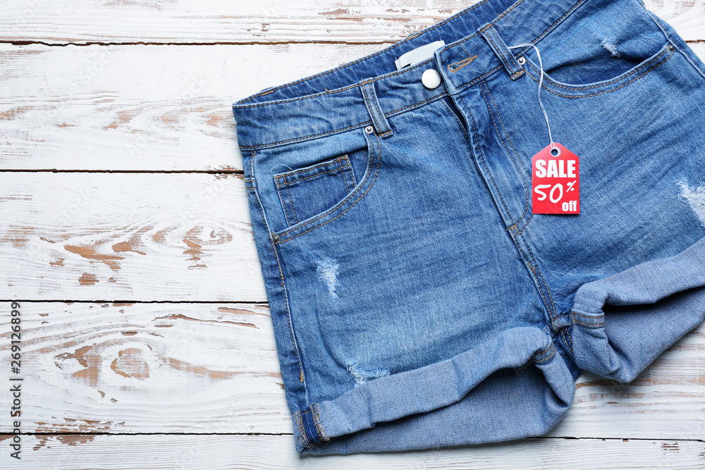 Jeans shorts with shopping tag on white wooden background