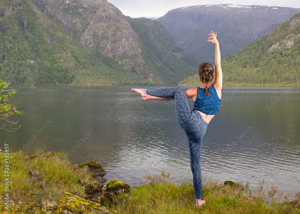 Young woman is practicing yoga at mountain lake.