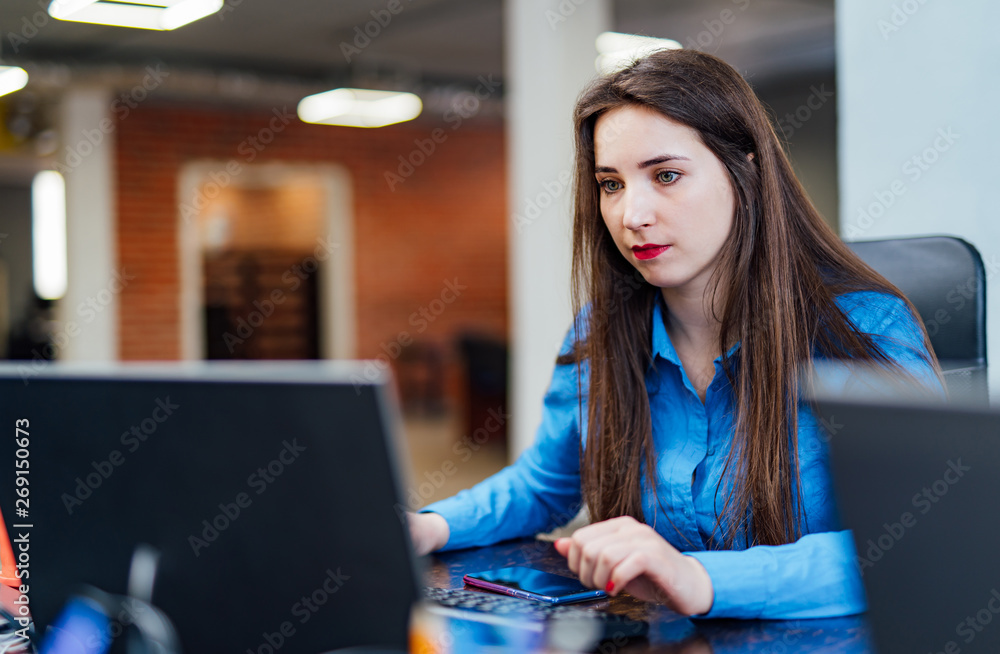专注的女性开发人员正在现代办公室的电脑上工作。有吸引力的年轻女性项目