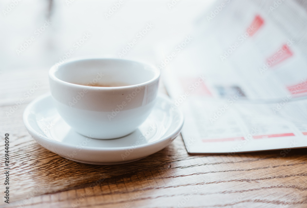 大c旁边的木桌上放着一杯黑咖啡和新鲜的运动报纸的静物图像