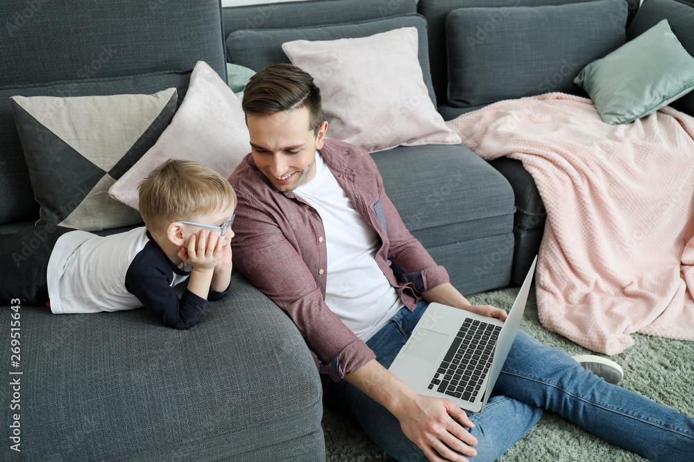 年轻的父亲带着小儿子在家看动画片