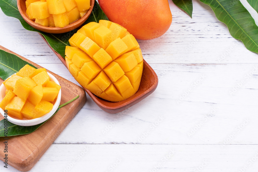 Fresh chopped mango on a tray and bright rustic wooden background. Tropical summer fruit design conc