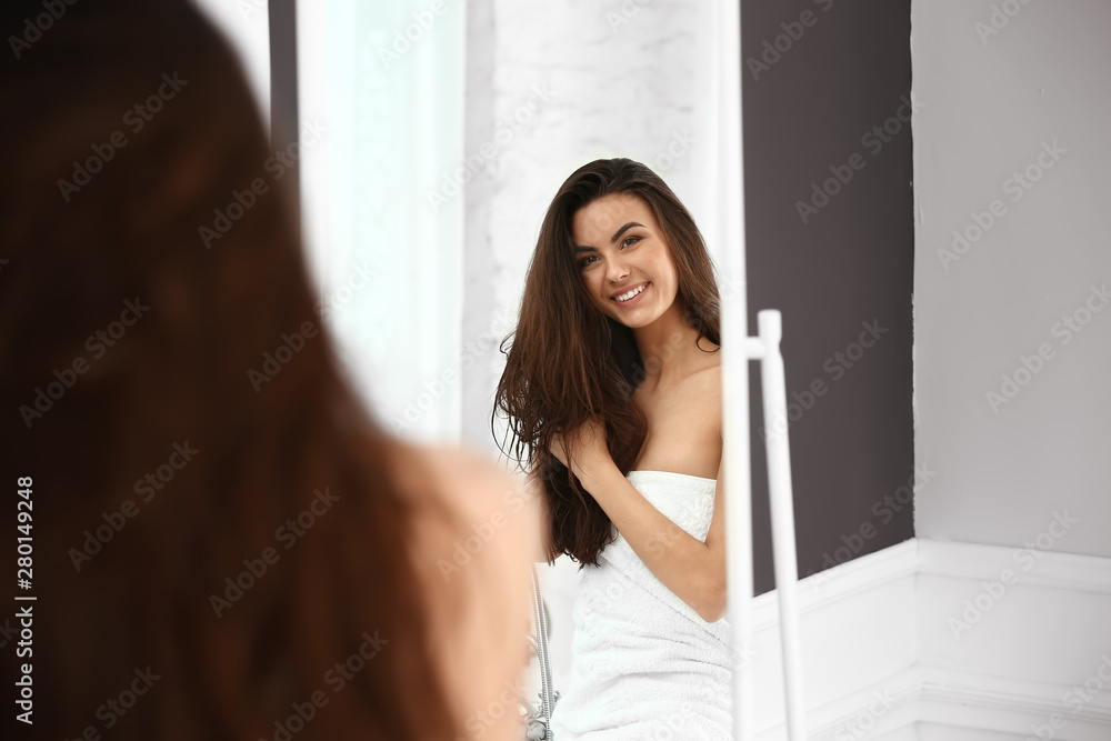 美丽的年轻女人，留着健康的长发，在家照镜子