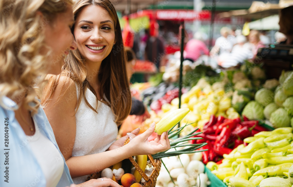 年轻女性在市场上购买健康的蔬菜和水果