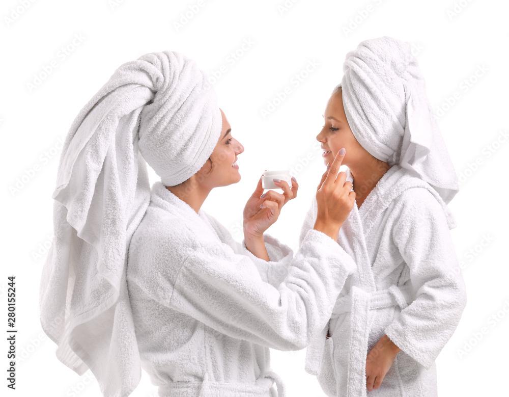 母亲在白色背景下给小女儿脸上涂面霜